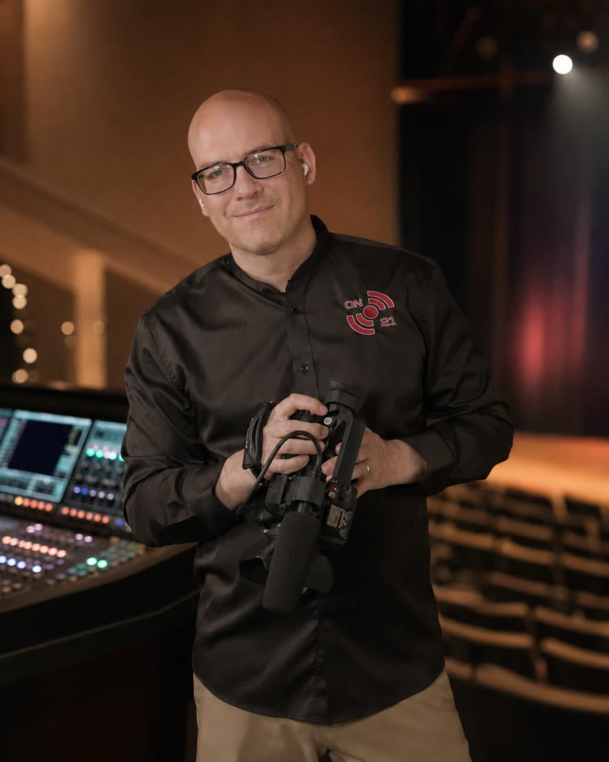 ON21 Founder and Lead Producer holding a video camera in a performing arts venue
